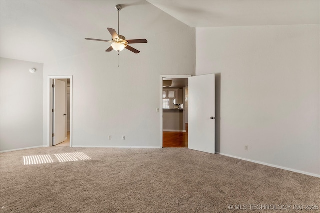 carpeted spare room featuring baseboards, high vaulted ceiling, and a ceiling fan