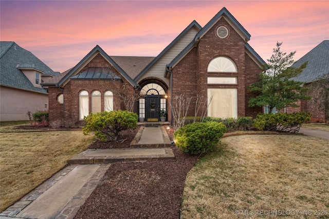 view of front of home with a lawn, french doors, and brick siding