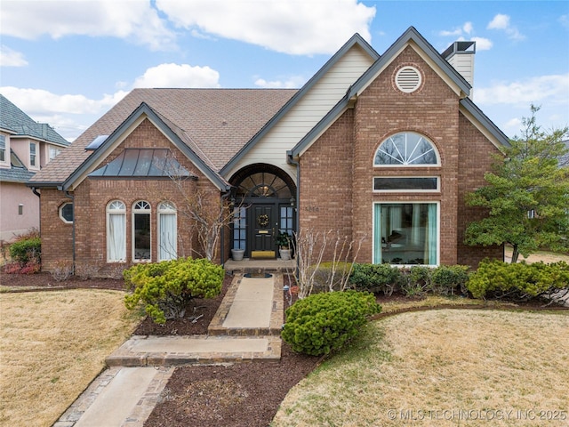 view of front of home with brick siding, a chimney, and a front yard