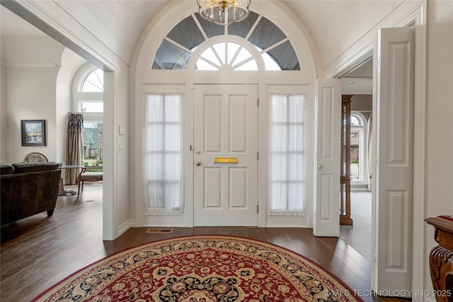 foyer entrance with visible vents, an inviting chandelier, dark wood-style floors, and vaulted ceiling