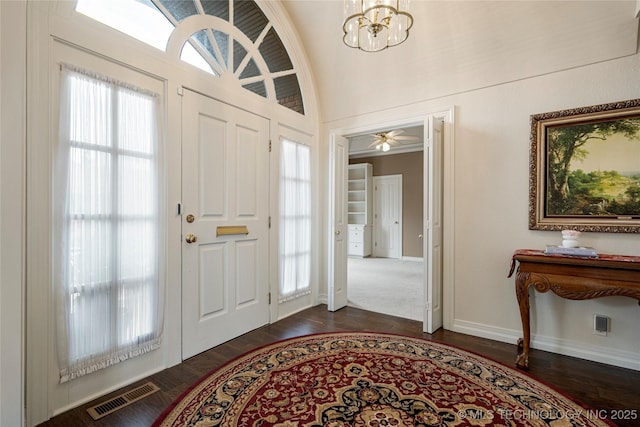 foyer entrance featuring visible vents, lofted ceiling, dark wood-style floors, an inviting chandelier, and baseboards