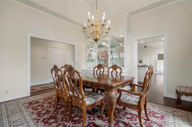 dining room with a notable chandelier, crown molding, baseboards, and wood finished floors