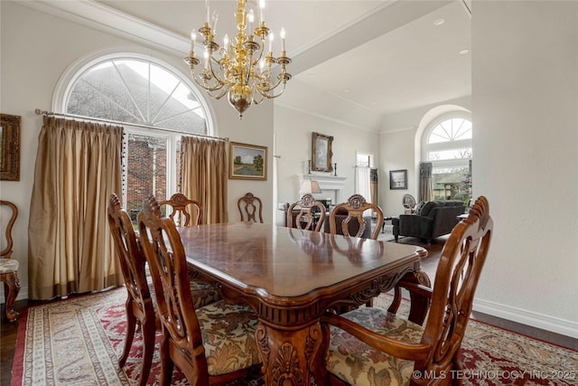 dining room with wood finished floors, a fireplace, baseboards, and a chandelier