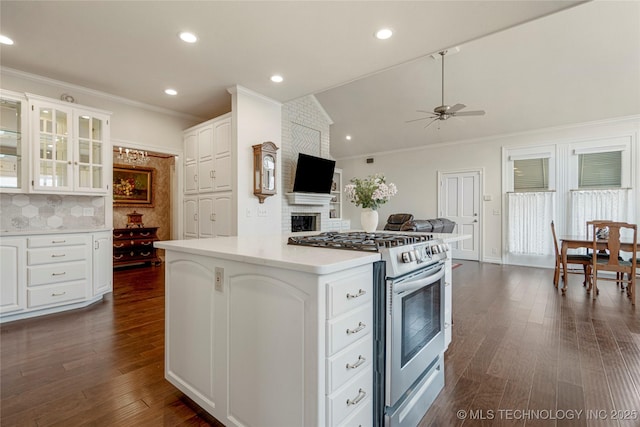 kitchen with dark wood finished floors, decorative backsplash, gas range, and white cabinetry