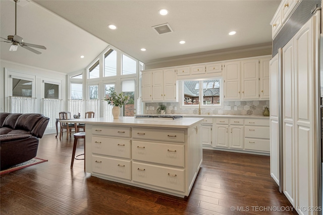 kitchen with paneled refrigerator, visible vents, a kitchen island, open floor plan, and dark wood finished floors