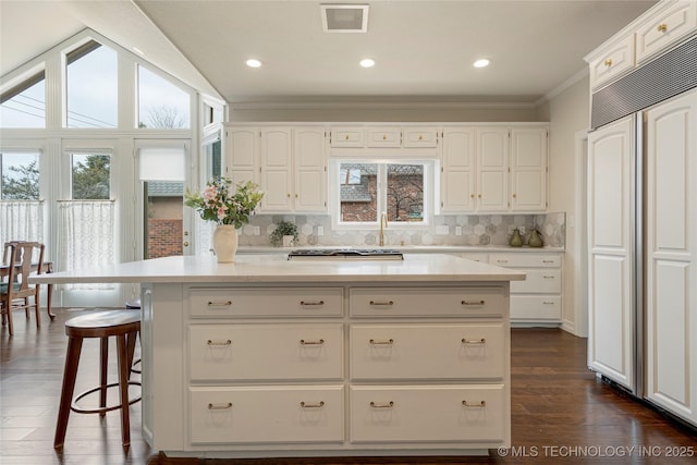 kitchen with paneled refrigerator, visible vents, plenty of natural light, and white cabinetry