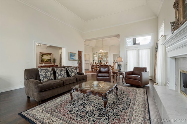 living room featuring baseboards, ornamental molding, dark wood-type flooring, a towering ceiling, and a tiled fireplace