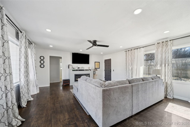 living area featuring dark wood-style floors, a glass covered fireplace, and recessed lighting