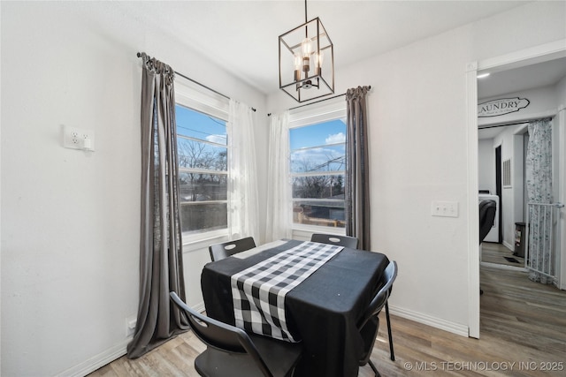 dining area featuring baseboards, a chandelier, and wood finished floors