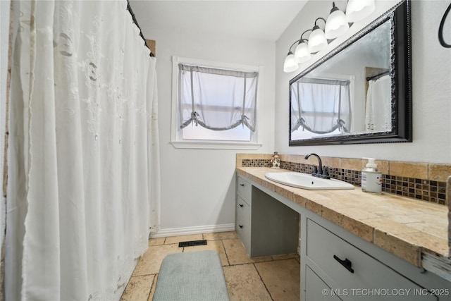 full bathroom featuring stone tile floors, visible vents, decorative backsplash, vanity, and baseboards