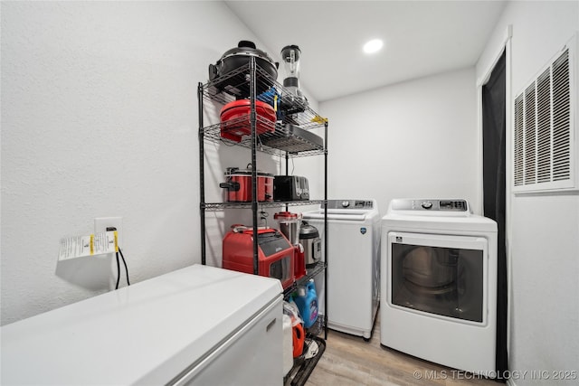 clothes washing area with laundry area, washer and clothes dryer, light wood-style floors, and recessed lighting