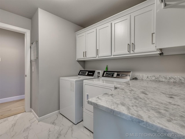 laundry room featuring cabinet space, baseboards, marble finish floor, and washing machine and clothes dryer