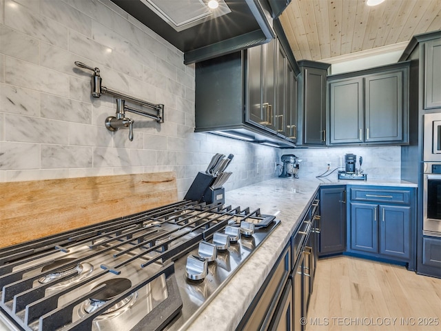 kitchen featuring tasteful backsplash, wooden ceiling, light wood-style flooring, appliances with stainless steel finishes, and light stone countertops