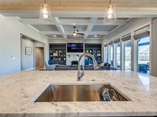 kitchen featuring built in features, a fireplace, a sink, coffered ceiling, and beamed ceiling