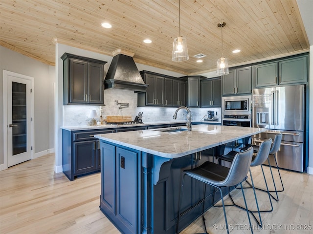 kitchen featuring appliances with stainless steel finishes, wood ceiling, premium range hood, and a sink