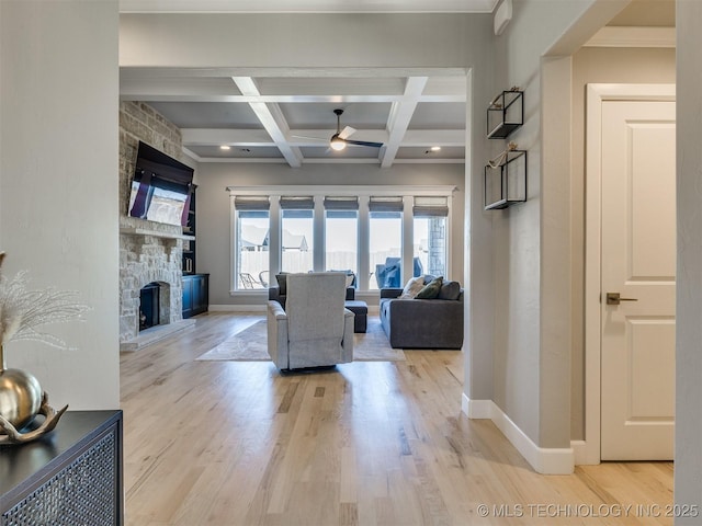 living room featuring light wood-style floors, a fireplace, baseboards, and coffered ceiling