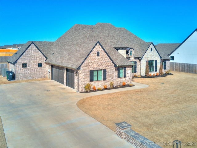 view of front of property with a garage, brick siding, fence, concrete driveway, and roof with shingles