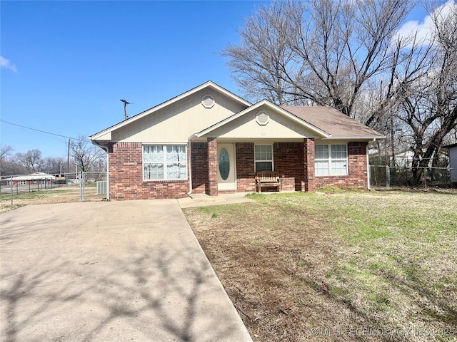 single story home featuring brick siding, a porch, fence, and a front yard