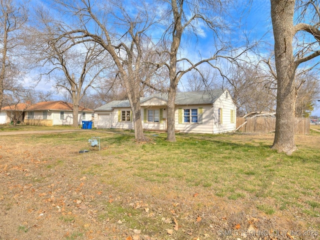 view of front facade with an attached garage, a front lawn, and fence