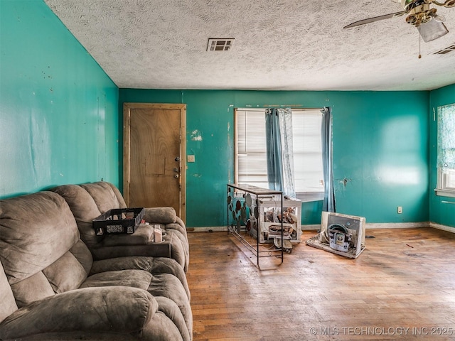 living room featuring visible vents, baseboards, and wood finished floors