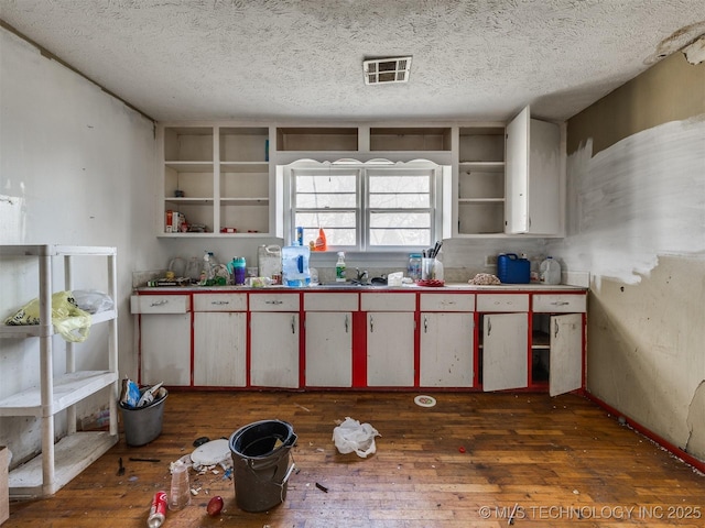 kitchen featuring red cabinets, open shelves, visible vents, a textured ceiling, and hardwood / wood-style flooring