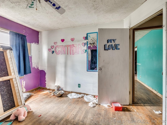 unfurnished bedroom featuring wood-type flooring, a textured ceiling, and baseboards