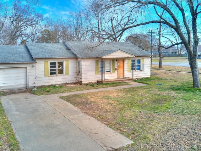 single story home with a shingled roof, a front yard, concrete driveway, and an attached garage