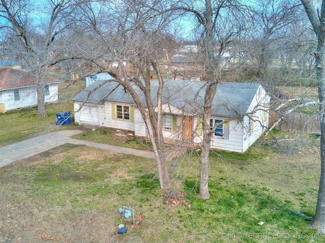 view of front of house featuring a shingled roof, driveway, and a front lawn