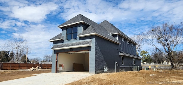 view of front of home featuring a shingled roof, fence, an attached garage, and central AC unit