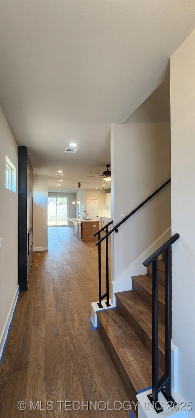 interior space with visible vents, baseboards, hardwood / wood-style floors, stairs, and a sink