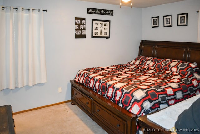 bedroom with light colored carpet and baseboards