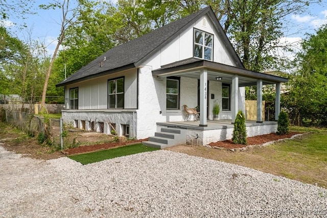 view of front of property with a shingled roof, covered porch, and fence