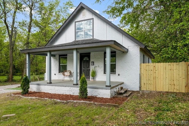 view of front of home featuring fence, a porch, and stucco siding