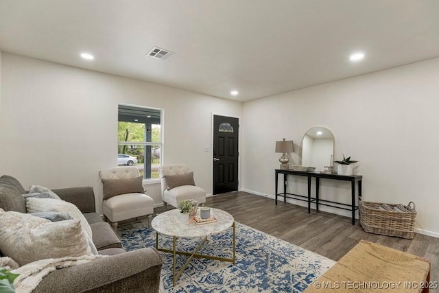 living area with recessed lighting, visible vents, baseboards, and wood finished floors