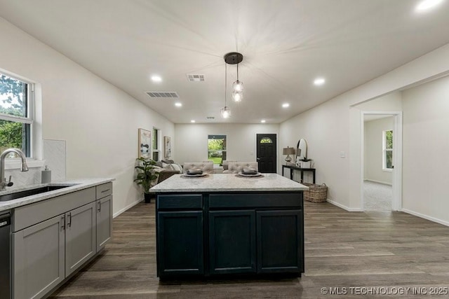 kitchen with dark wood-style flooring, visible vents, a sink, and dishwashing machine