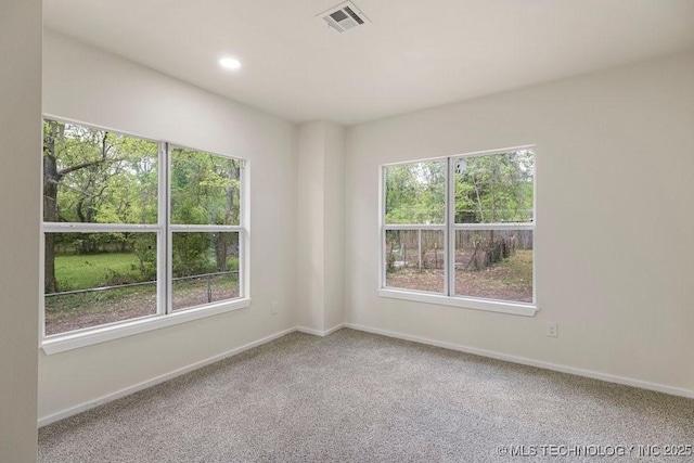 empty room with carpet floors, a healthy amount of sunlight, and visible vents