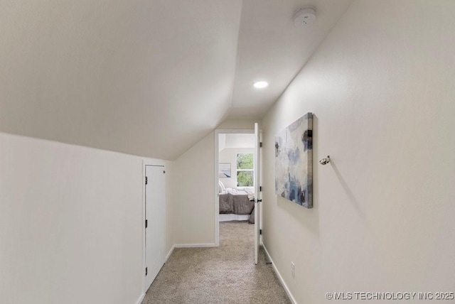 hallway featuring carpet, baseboards, and vaulted ceiling