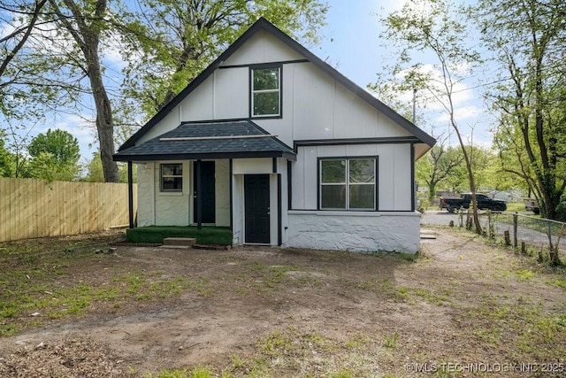 view of front of property with a shingled roof and fence