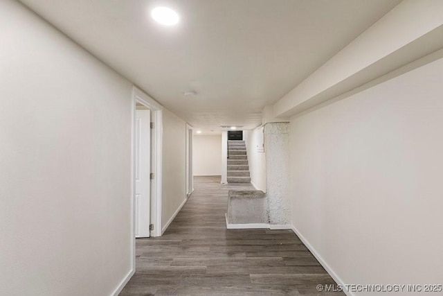 corridor with dark wood-style floors, stairs, and baseboards