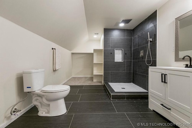 bathroom featuring baseboards, tiled shower, vanity, and toilet