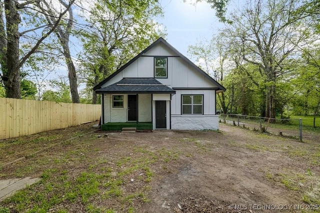 view of front of home with board and batten siding, a fenced backyard, and roof with shingles