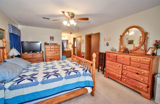 bedroom with light carpet, ceiling fan, visible vents, and ensuite bath