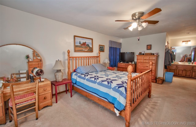 bedroom featuring a ceiling fan, light carpet, and ensuite bath