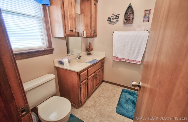 bathroom with vanity, toilet, and baseboards