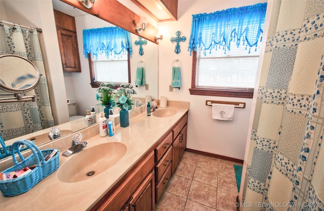 full bathroom featuring plenty of natural light, tile patterned floors, a sink, and double vanity