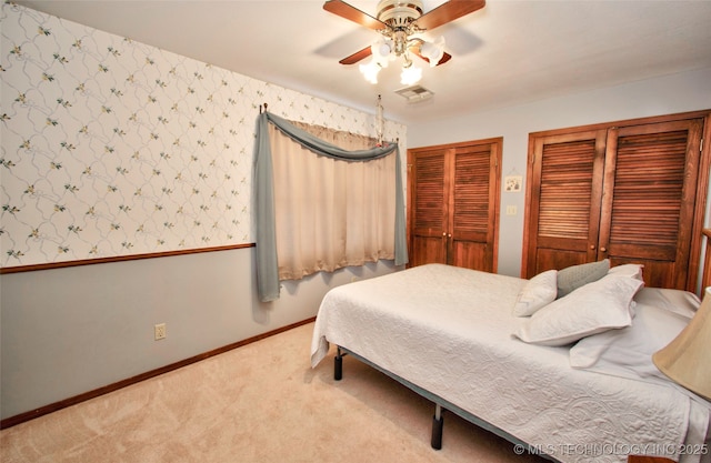 bedroom featuring carpet, two closets, visible vents, and wallpapered walls