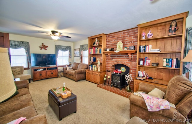 living area with a ceiling fan, carpet, and a wood stove