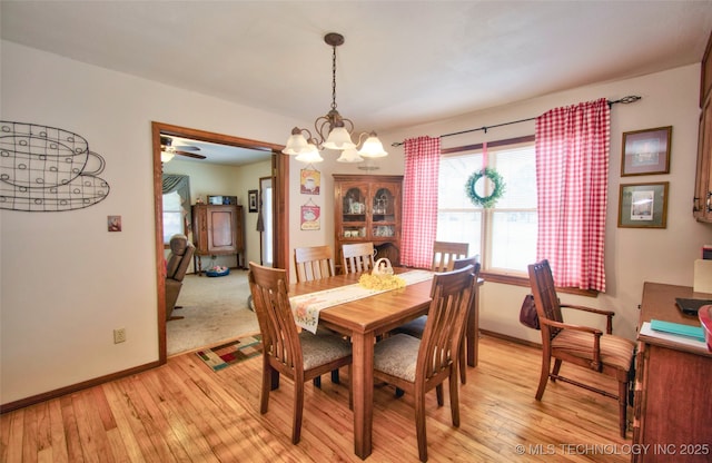 dining space featuring baseboards, light wood finished floors, and an inviting chandelier