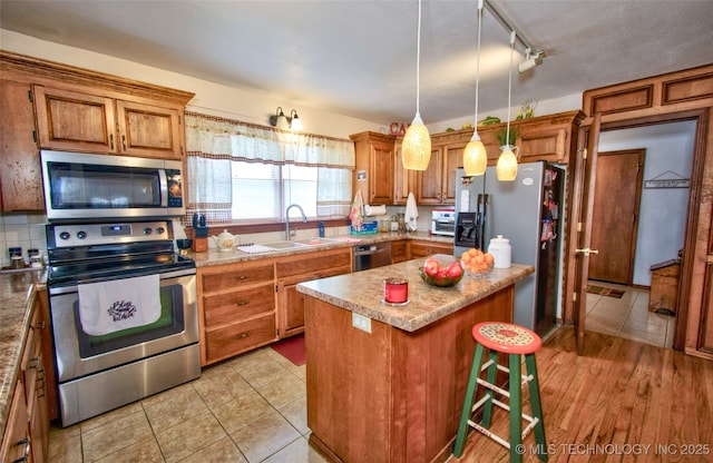 kitchen with a center island, brown cabinets, a breakfast bar area, stainless steel appliances, and a sink