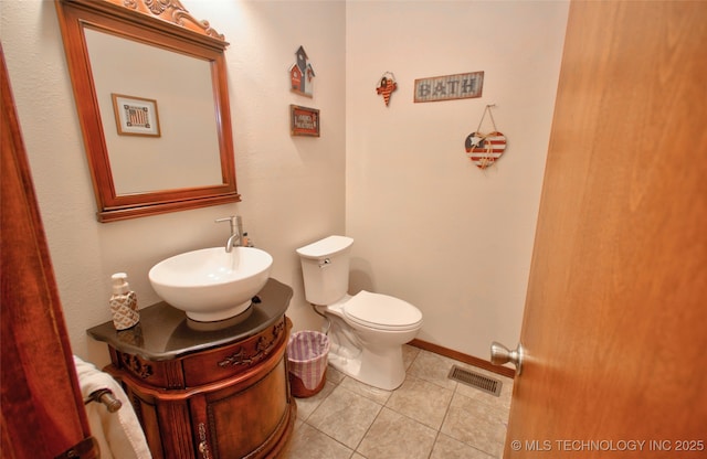 half bathroom featuring toilet, vanity, baseboards, visible vents, and tile patterned floors